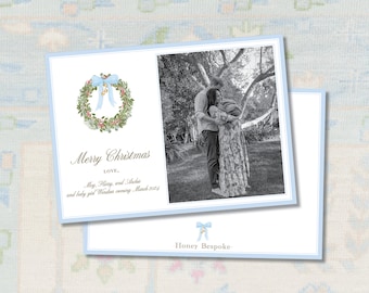 Pode incluir: Cartão de Natal com uma borda azul clara, apresentando uma coroa de flores em aquarela com um laço azul. O cartão inclui uma foto em preto e branco e o texto "Merry Christmas" e "Honey Bespoke".