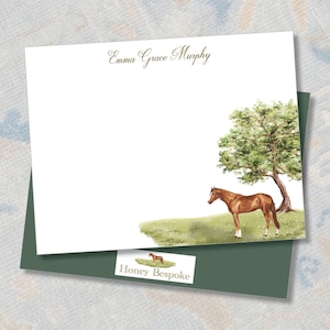 May include: Personalized stationery featuring a watercolor illustration of a brown horse standing in a field with a green tree. The stationery is white with the name "Emma Grace Murphy" printed at the top and "Honey Bespoke" at the bottom.