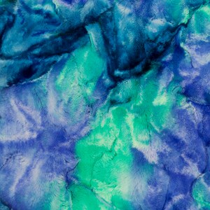 May include: A close-up of a blue and green faux fur fabric with a tie-dye pattern.
