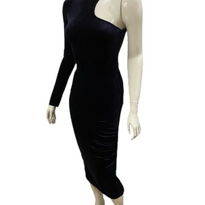 May include: A black velvet midi dress with a one-shoulder design and a cut-out detail at the shoulder.