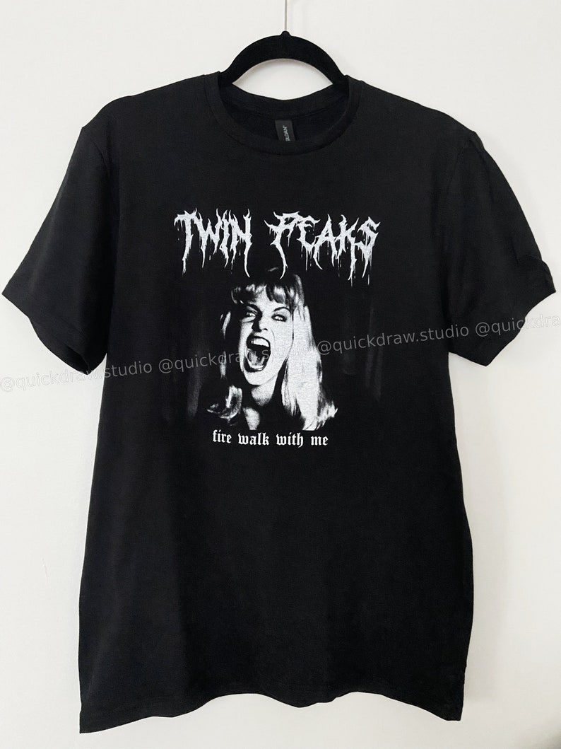 May include: Black t-shirt with a white graphic print of a woman with blonde hair screaming. The text "Twin Peaks" is above the woman's head in a metal font. The text "fire walk with me" is below the woman's head.