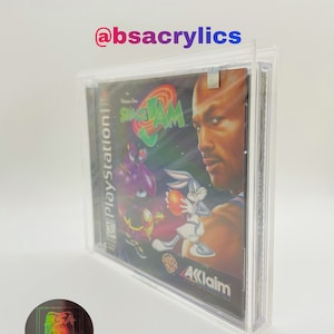 May include: A clear plastic case with a video game inside. The game is Space Jam for the Playstation. The case is in a protective acrylic display case. The text on the case reads "Space Jam" and "Playstation". The text "Akklaim" is visible on the bottom of the case. The text "*Game Not Included" is visible below the case.