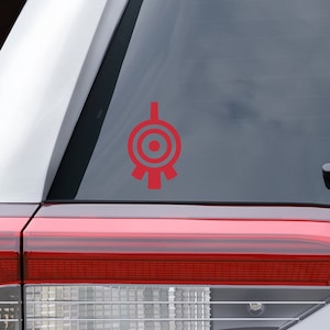 May include: A red vinyl decal of the "Symbol of the Ancients" from the TV show Stargate SG-1, applied to the rear window of a silver SUV.