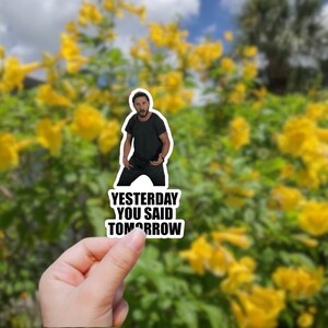 May include: A sticker featuring a man with a beard and black shirt, with the text "Yesterday you said tomorrow".
