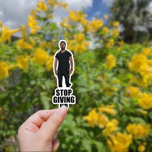 May include: A sticker featuring a man in a black shirt and jeans with the text "STOP GIVING UP" in black letters.