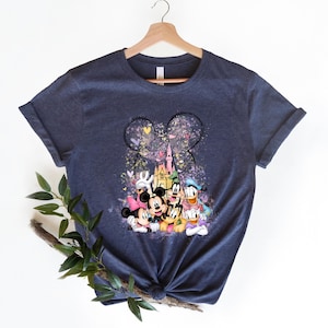 May include: A navy blue t-shirt with a graphic print of Mickey Mouse and friends in front of Cinderella's Castle. The graphic is surrounded by pink, purple, and blue hearts and stars.