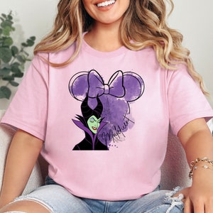 a woman sitting on a couch wearing a pink shirt