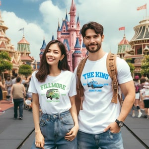 May include: Two people wearing white t-shirts with Disney Cars graphics. One shirt says "Fillmore" with a green van illustration, the other says "The King" with a blue race car. Both shirts have the "Disney Cars" logo.