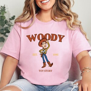 a woman sitting on a couch wearing a woody t - shirt