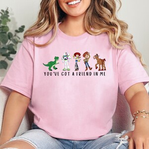 a woman wearing a pink t - shirt that says you've got a friend