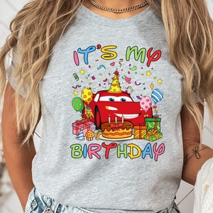 a woman wearing a birthday shirt with cars on it