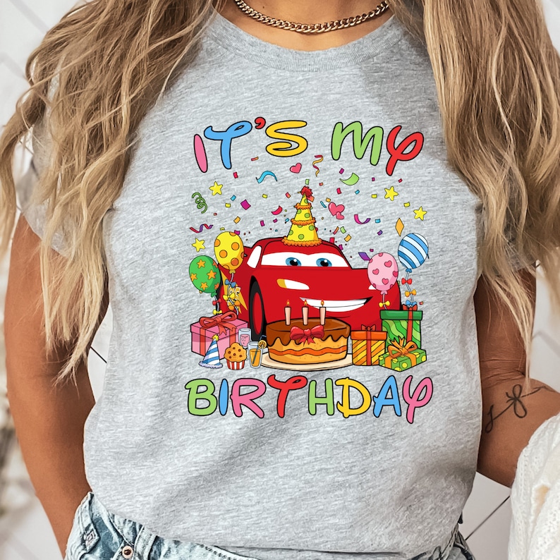 a woman wearing a birthday shirt with cars on it