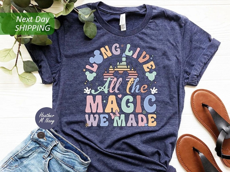 May include: A navy blue t-shirt with a rainbow colored graphic that says "Long Live All the Magic We Made". The graphic features a silhouette of the Cinderella Castle and Mickey Mouse ears.
