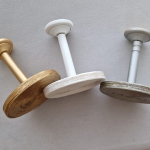 May include: Three decorative wall hooks with round bases. The hooks are made of wood and painted in gold, white and grey.