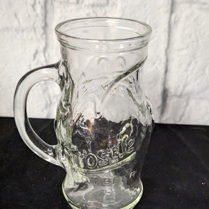 May include: A clear glass mug with a handle. The mug has a raised design and the word "Frostbite" is embossed on the side.