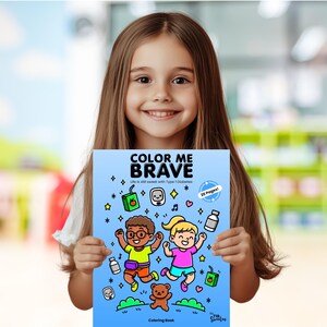 Puede incluir: Una persona joven sostiene un libro para colorear azul titulado "Color Me Brave: Life is still sweet with Type 1 Diabetes". La portada presenta una ilustraci&oacute;n de dibujos animados de dos ni&ntilde;os saltando con un osito de peluche y otros art&iacute;culos relacionados con la diabetes.
