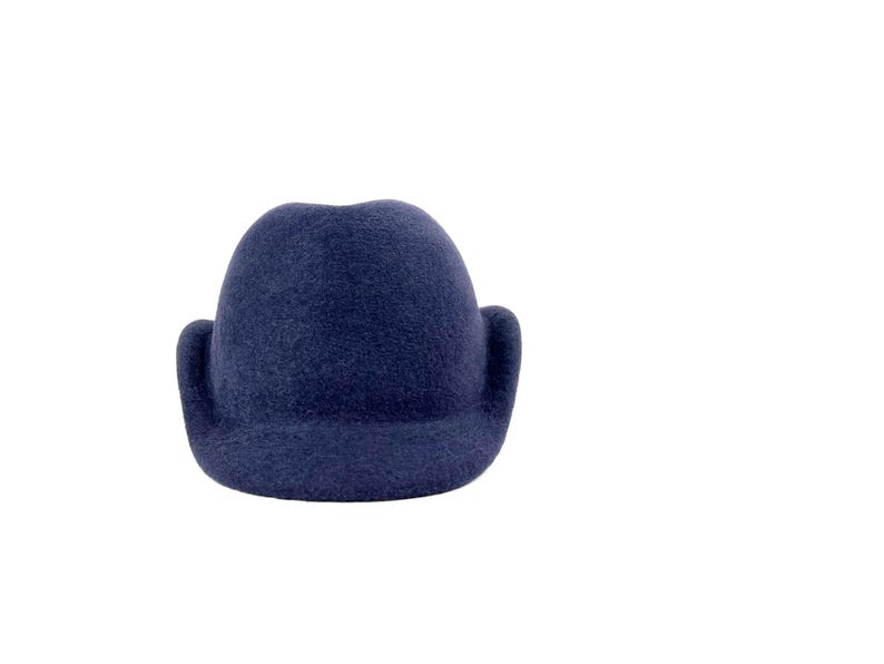 front view of a navy wool velour hat with a structured crown, mock ear flaps, and a short brim, displayed on a white background