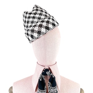 Könnte beinhalten: Ein schwarz-weiß kariertes Hut mit einer spitzen Krone. Der Hut sitzt auf einem rosafarbenen Mannequin-Kopf. Das Mannequin trägt ein schwarz-weißes Bandana.