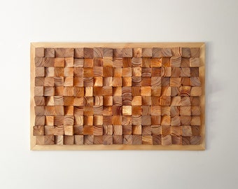 Puede incluir: Una pieza de arte de pared rectangular de madera hecha de pequeños bloques de madera cuadrados dispuestos en un patrón escalonado. Los bloques son de color marrón claro y tienen una veta de madera natural.