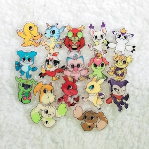 Peut inclure: Une collection de 17 épingles de personnages de dessins animés colorés. Les épingles présentent divers personnages de la série d'anime Digimon, notamment Agumon, Gabumon et Guilmon. Les épingles sont en acrylique transparent et ont une finition brillante.