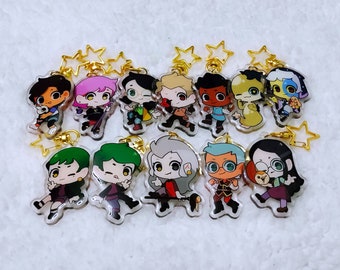 May include: A set of 12 colorful cartoon character keychains with gold star charms. The characters are all different and include a variety of colors and designs.