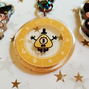 May include: Yellow triangle-shaped character with one eye and a bow tie, inside a clear round keychain with a yellow circle and symbols around the edge.