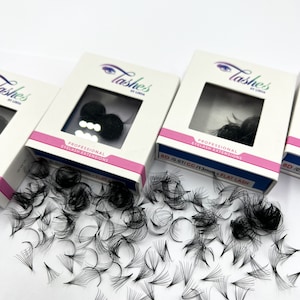 May include: Three boxes of black eyelash extensions with the brand name "Lashes by Linda" printed on the front. The boxes are white with pink accents and feature a close-up image of the eyelashes. The text "Professional Eyelash Extensions" is printed on the front of the boxes. The boxes are labeled with the size and type of lashes: "BD 10.07/CC/13mm - Flat Lash" and "8D/0.07/CC/13mm - Flat Lash".