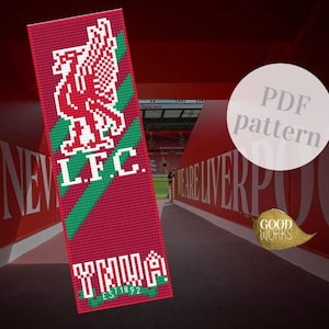 Op de afbeelding: Een rood en groen Liverpool FC boekenlegger met het logo en de initialen van het team. De boekenlegger heeft de tekst "YNWA EST 1892". De achtergrond toont een stadiontunnel.