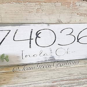 May include: White wooden sign with black painted text. The sign reads "74036 - Inola, Ok - @TeamGreenCreations".