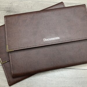 Brown cabrini board-supported document wallets front cover with square nickel corners and silver foil personalisation in the centre of the wallet that reads documents.