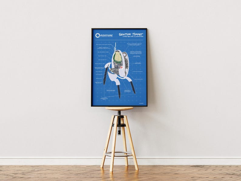 May include: A framed blueprint-style poster featuring a diagram of an Aperture Science Sentry Turret. The poster has a blue background with white and black details, including the Aperture Science logo and the words "Sentry Turret". The poster is displayed on a wooden stool.