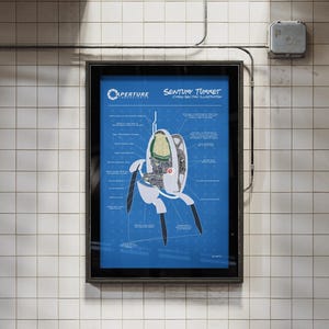 May include: A framed poster featuring a blueprint-style illustration of a "Sentry Turret" from the video game Portal. The poster has a blue background with white and black details, and is mounted on a tiled wall.