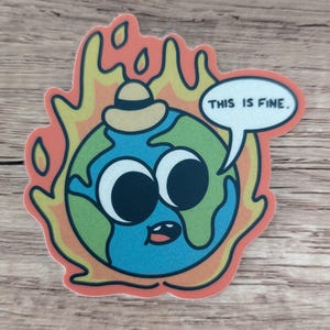 K&ouml;nnte beinhalten: Eine Cartoon-Illustration der Erde, die einen Hut tr&auml;gt und von Flammen verschlungen wird, mit einer Sprechblase, die "Das ist in Ordnung." sagt.