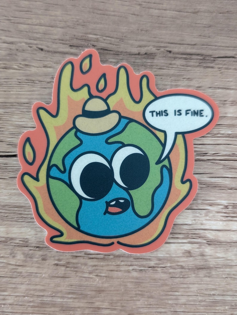 K&ouml;nnte beinhalten: Eine Cartoon-Illustration der Erde, die einen Hut tr&auml;gt und von Flammen verschlungen wird, mit einer Sprechblase, die "Das ist in Ordnung." sagt.