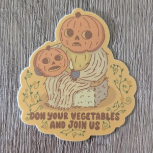 May include: A sticker with a cartoon pumpkin wearing a sweater and holding a smaller pumpkin. The sticker has a yellow background with the text "Don your vegetables and join us".