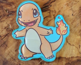 May include: A cartoon image of Charmander, a popular character from the Pokemon franchise. The orange and tan Charmander is outlined in black and set against a light blue background. A flame is on the end of its tail.