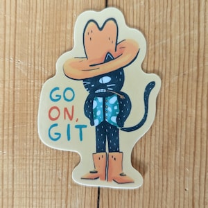 May include: A black cat wearing a cowboy hat and a blue and white patterned vest. The cat is standing with its legs spread apart and has a long tail. The text "GO ON, GIT" is written in red, orange, and blue letters below the cat.