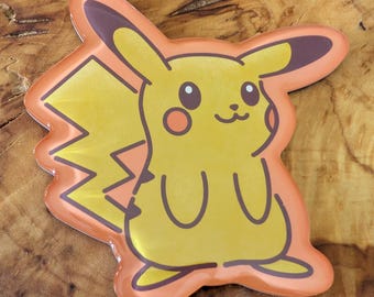May include: A yellow Pikachu character sticker with a light orange outline. The sticker features the iconic lightning bolt tail and rosy cheeks. The design is a cartoon style.