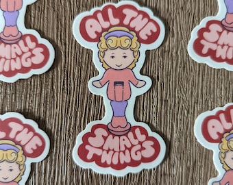 May include: A set of stickers featuring a cartoon girl with blonde hair and a pink outfit standing on a cloud with the text "All the small things".