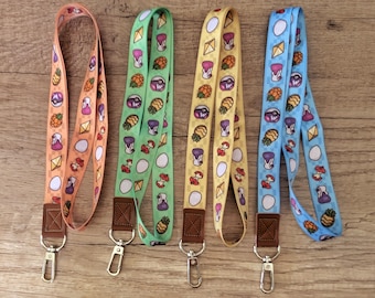 May include: Four colorful lanyards with various patterns. The lanyards are orange, green, yellow, and blue. Each lanyard features a repeating pattern of cartoon illustrations, including a pineapple, a mushroom, and an egg. They have brown leather-like attachments and silver metal clasps.