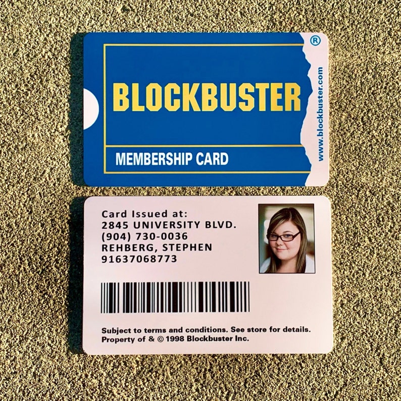 以下が含まれることがあります： バーコード、テキスト「Card Issued at: 2845 UNIVERSITY BLVD. (904) 730-0036 REHBERG, STEPHEN 91637068773」、および眼鏡をかけた女性の画像が印刷されたピンク色のブロックバスター会員カードです。