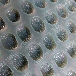 Puede incluir: Un molde de silicona con múltiples cavidades con forma de cerebro. El molde es gris claro y tiene el texto "LASER CRAFT" impreso.
