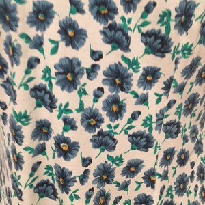 May include: White fabric with a blue and green floral pattern. The flowers are small and have a simple design.