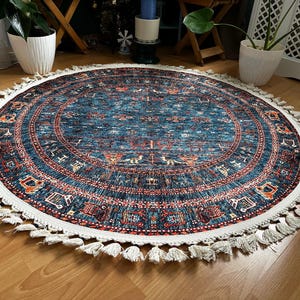 May include: A round blue and red rug with a white fringe. The rug has a traditional pattern with intricate details.