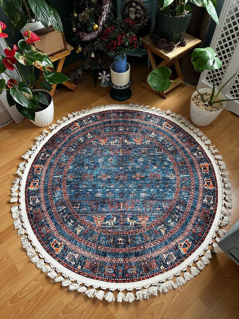 May include: A round blue rug with a white fringe border. The rug has a geometric pattern in shades of red, orange, and blue. The rug is on a wooden floor.