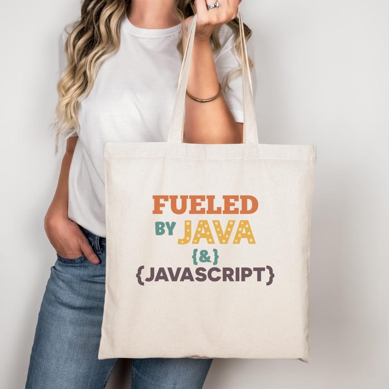 K&ouml;nnte beinhalten: Eine cremefarbene Tragetasche mit dem Text "Fueled by Java {&} JavaScript" in Orange, Gr&uuml;n, Gelb und Braun. Die Tasche hat zwei Henkel und wird von einer Person getragen, die ein wei&szlig;es T-Shirt und eine blaue Jeans tr&auml;gt.