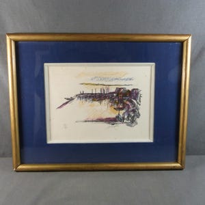 Può includere: Una stampa artistica di paesaggio astratto in una cornice dorata. L'opera presenta una scena sul lungomare con edifici e figure, in tonalità viola, arancione e nere. La stampa è incorniciata con un passe-partout blu.