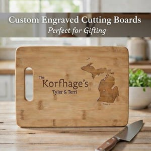 May include: A rectangular bamboo cutting board with a handle, engraved with a state outline and the text "The Korfhage's Tyler & Terri". The text "Custom Engraved Cutting Boards" is at the top.