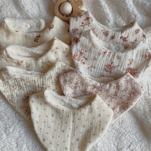 Puede incluir: Un conjunto de ocho baberos para bebé con una variedad de estampados florales. Los baberos están hechos de un material suave y absorbente y tienen un forro de felpa para mayor comodidad. Los baberos son en tonos crema, rosa y marrón.