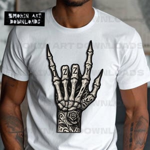 Puede incluir: Camiseta blanca con una ilustraci&oacute;n detallada de una mano de esqueleto haciendo el gesto de 'rock on', con la palabra 'OZZY' escrita en el centro. La mano tiene tatuajes florales. La esquina superior izquierda tiene el texto 'SMOKIN ART DOWNLOADS'.
